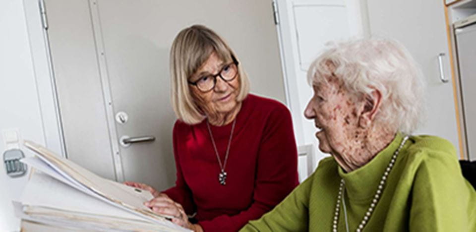 Ældre borger sidder sammen med dame og læser i en bog eller lignende