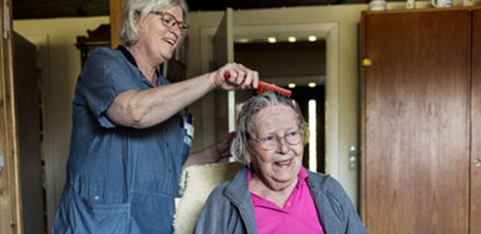 Ældre kvinde får hjælp til at rede går