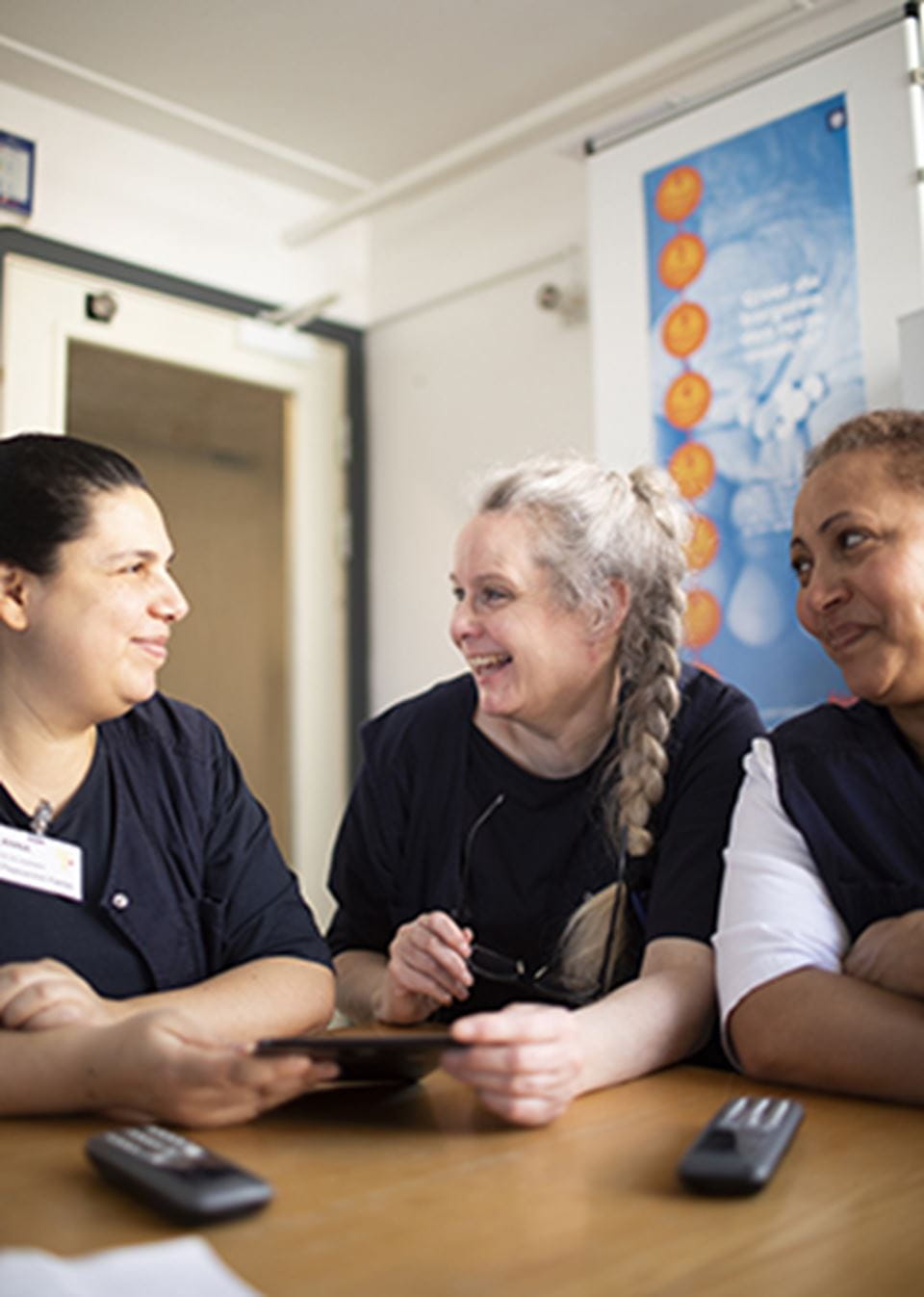 Tre personer i plejeuniformer i samtale 