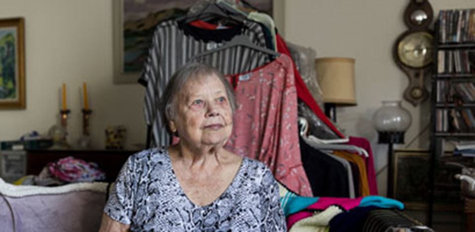 En ældre kvinde sidder i sit hjem og kigger ud